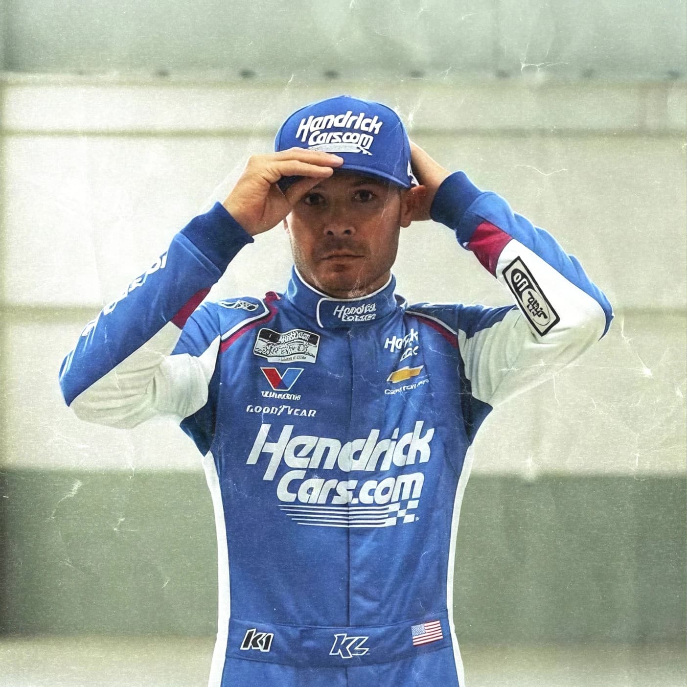 Kyle Larson adjusts his cap in his blue Hendrick firesuit