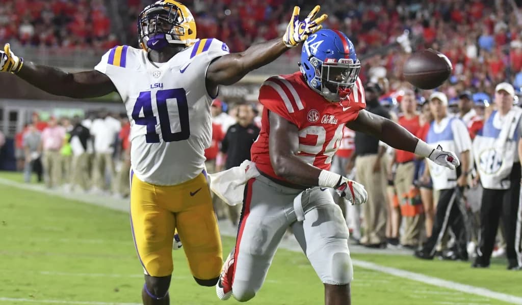 An LSU defender reaches in to break up a pass intended for an Ole Miss receiver in front of a packed home crowd
