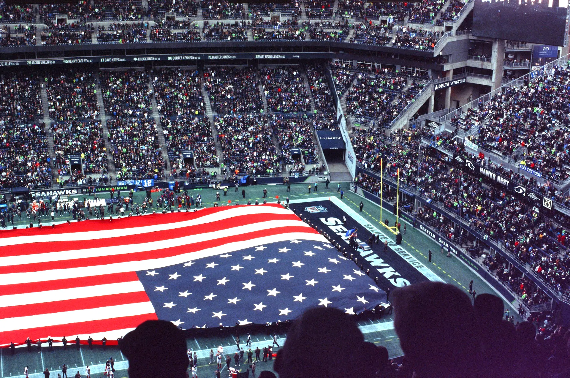 NFL stadium crowd with a giant United States flag unfurled across the field