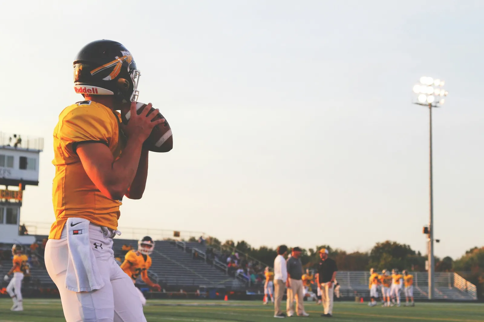 Quarterback in a gold jersey sets to throw during pregame warmups