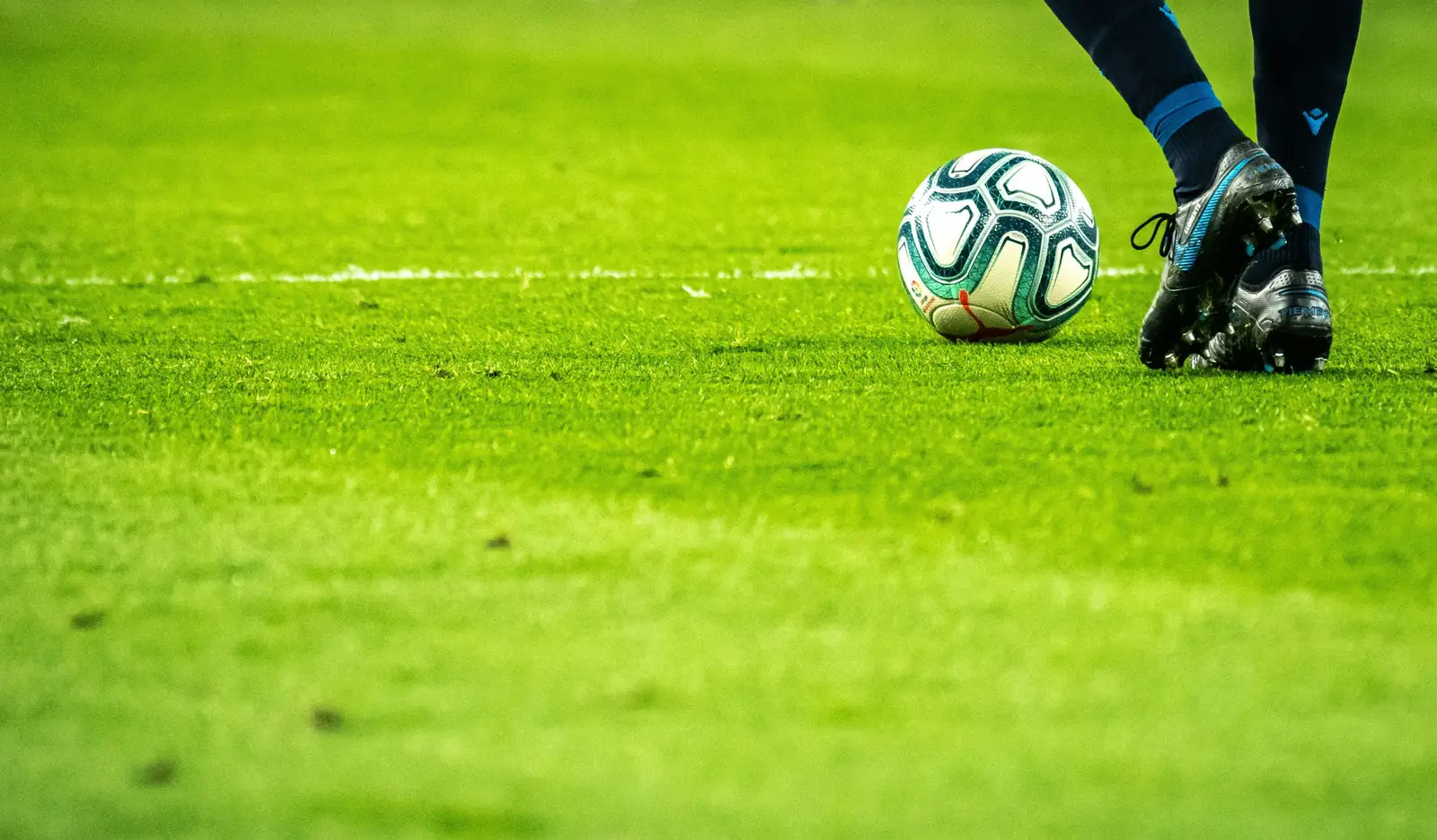 Player in blue socks and cleats stepping toward a ball on the pitch